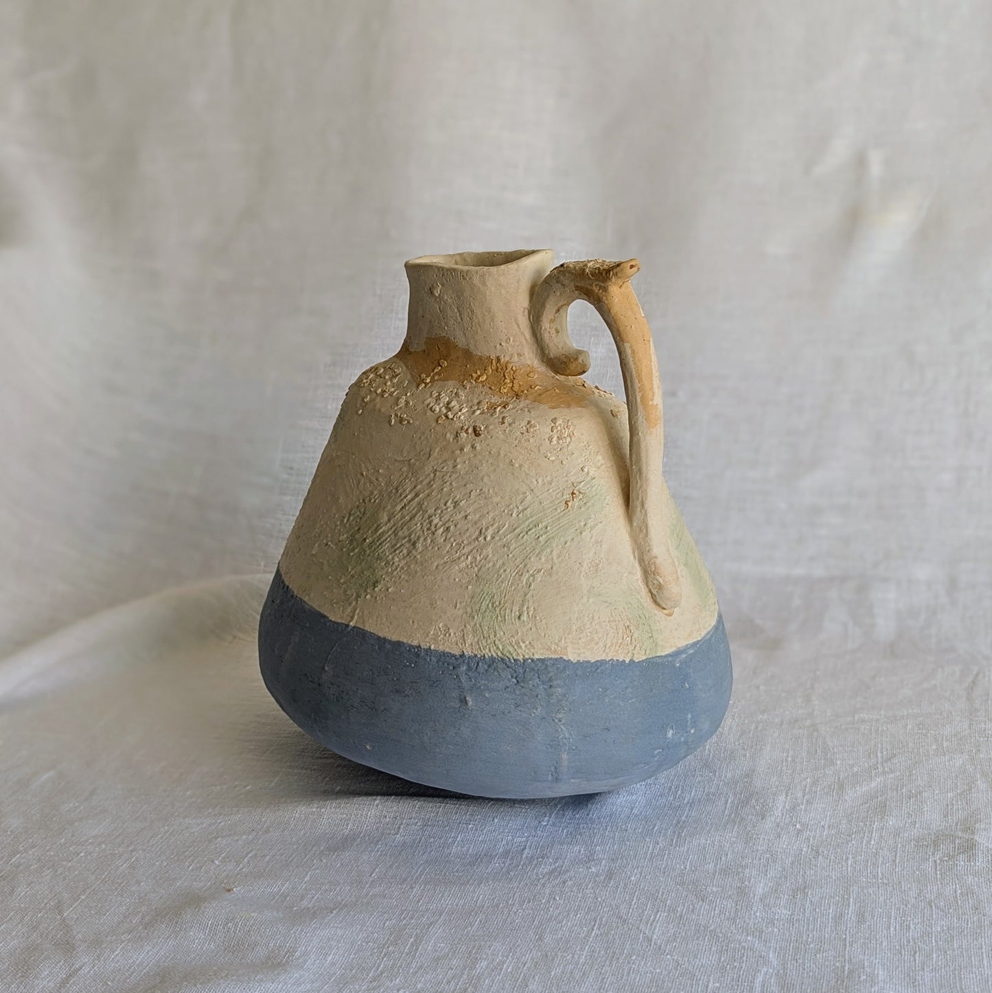 Pieza artesanal de barro rojo con técnica de churro, decorada con engobes y óxidos metálicos en tonos azul, blanco y terroso