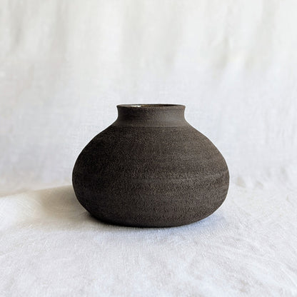 Pieza decorativa en gres negro artesanal, exterior mate con textura granulada y interior esmaltado brillante, 19 × 19 × 13 cm.