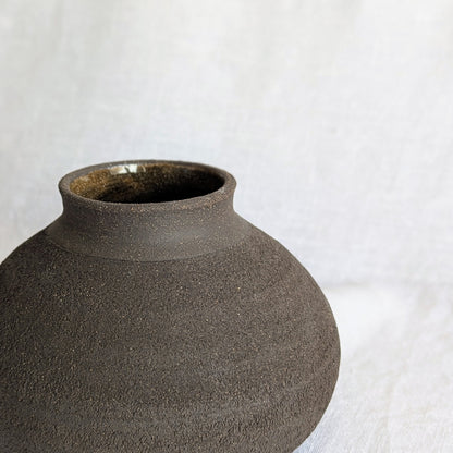 Pieza decorativa en gres negro artesanal, exterior mate con textura granulada y interior esmaltado brillante, 19 × 19 × 13 cm.