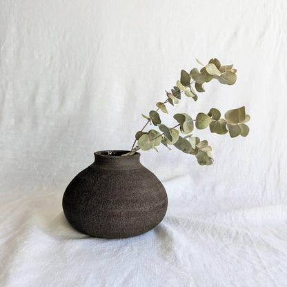 Pieza decorativa en gres negro artesanal, exterior mate con textura granulada y interior esmaltado brillante, 19 × 19 × 13 cm.