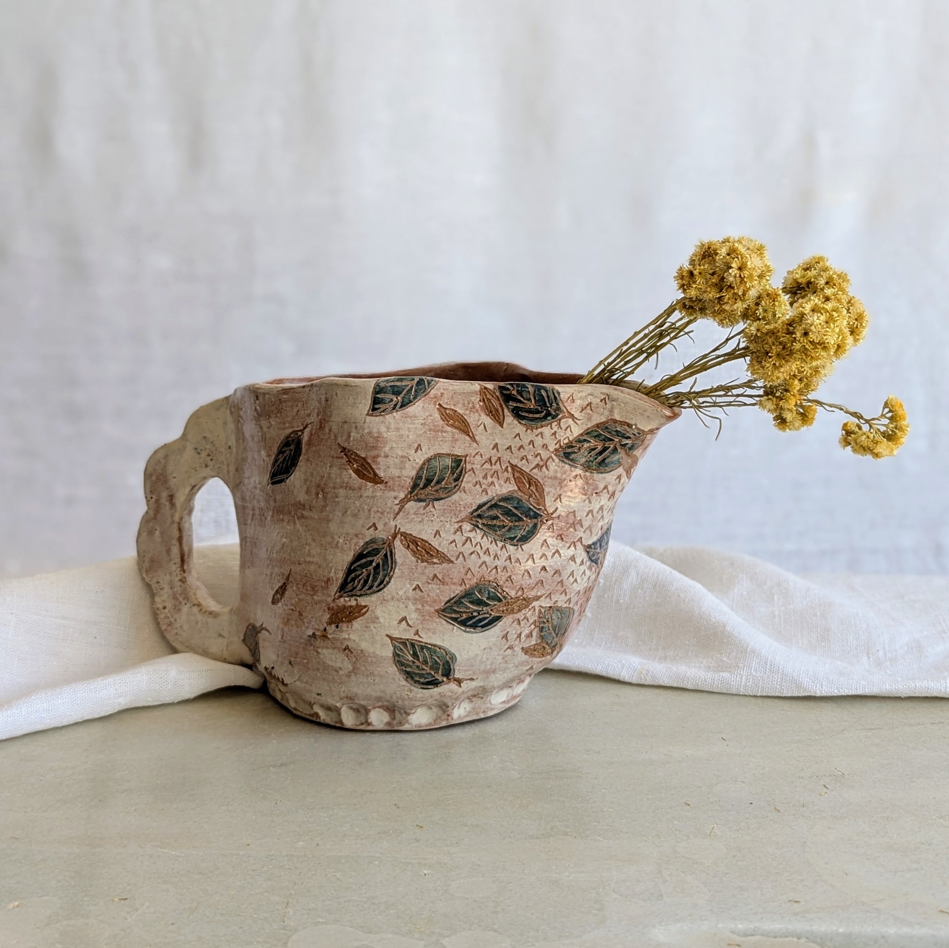 Pieza artesanal de barro rojo hecha a mano con técnica de churro y decoración esgrafiada de hojas naturales