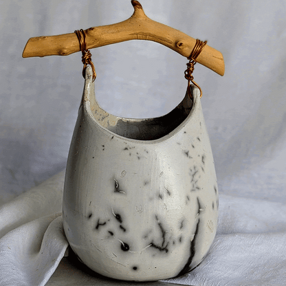 Pieza escultórica de gres blanco Rakú Naked con asa de rama de olivo y veladuras negras orgánicas, 20 × 13,5 × 26 cm.