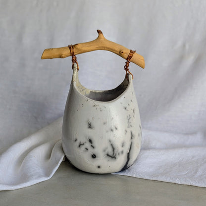 Pieza escultórica de gres blanco Rakú Naked con asa de rama de olivo y veladuras negras orgánicas, 20 × 13,5 × 26 cm.