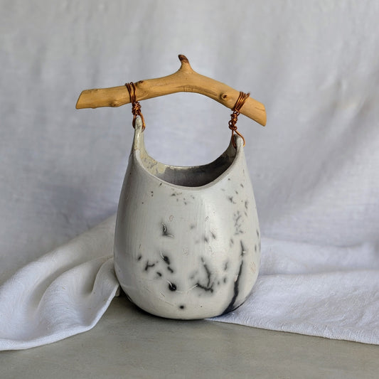 Pieza escultórica de gres blanco Rakú Naked con asa de rama de olivo y veladuras negras orgánicas, 20 × 13,5 × 26 cm.