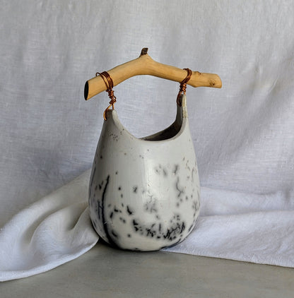 Pieza escultórica de gres blanco Rakú Naked con asa de rama de olivo y veladuras negras orgánicas, 20 × 13,5 × 26 cm.