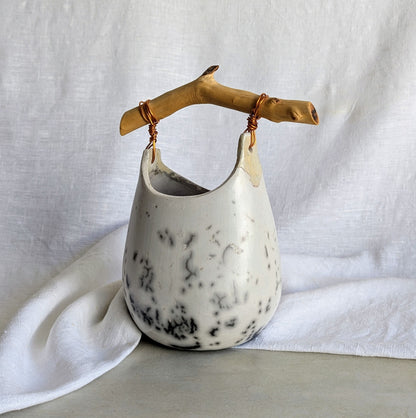 Pieza escultórica de gres blanco Rakú Naked con asa de rama de olivo y veladuras negras orgánicas, 20 × 13,5 × 26 cm.