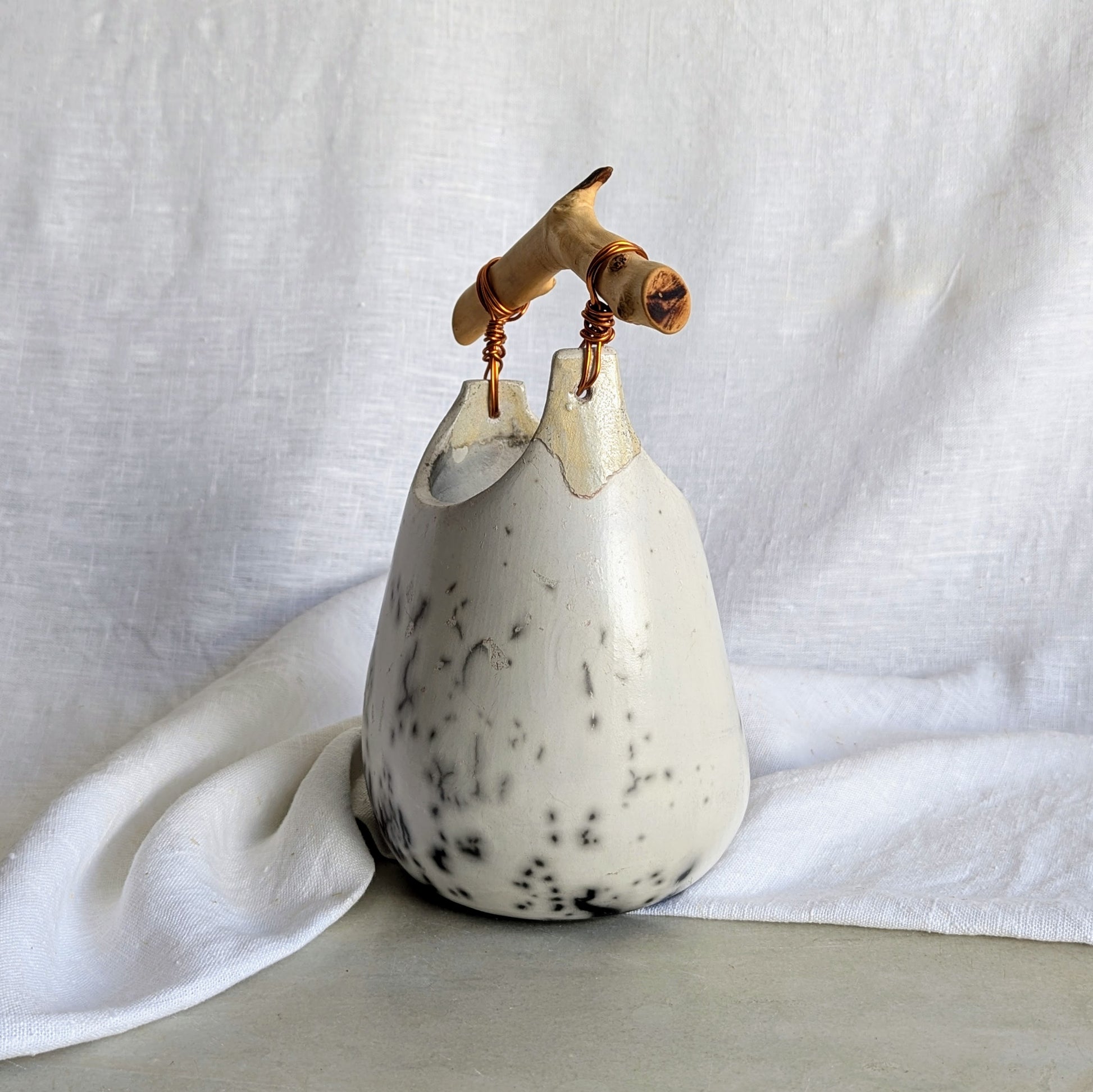 Pieza escultórica de gres blanco Rakú Naked con asa de rama de olivo y veladuras negras orgánicas, 20 × 13,5 × 26 cm.