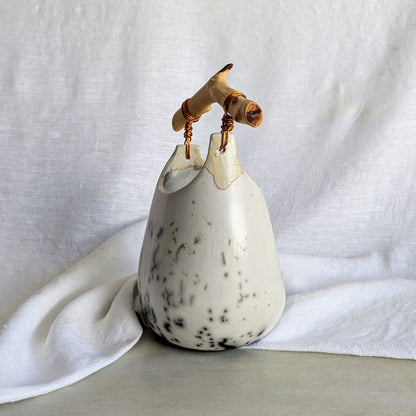 Pieza escultórica de gres blanco Rakú Naked con asa de rama de olivo y veladuras negras orgánicas, 20 × 13,5 × 26 cm.