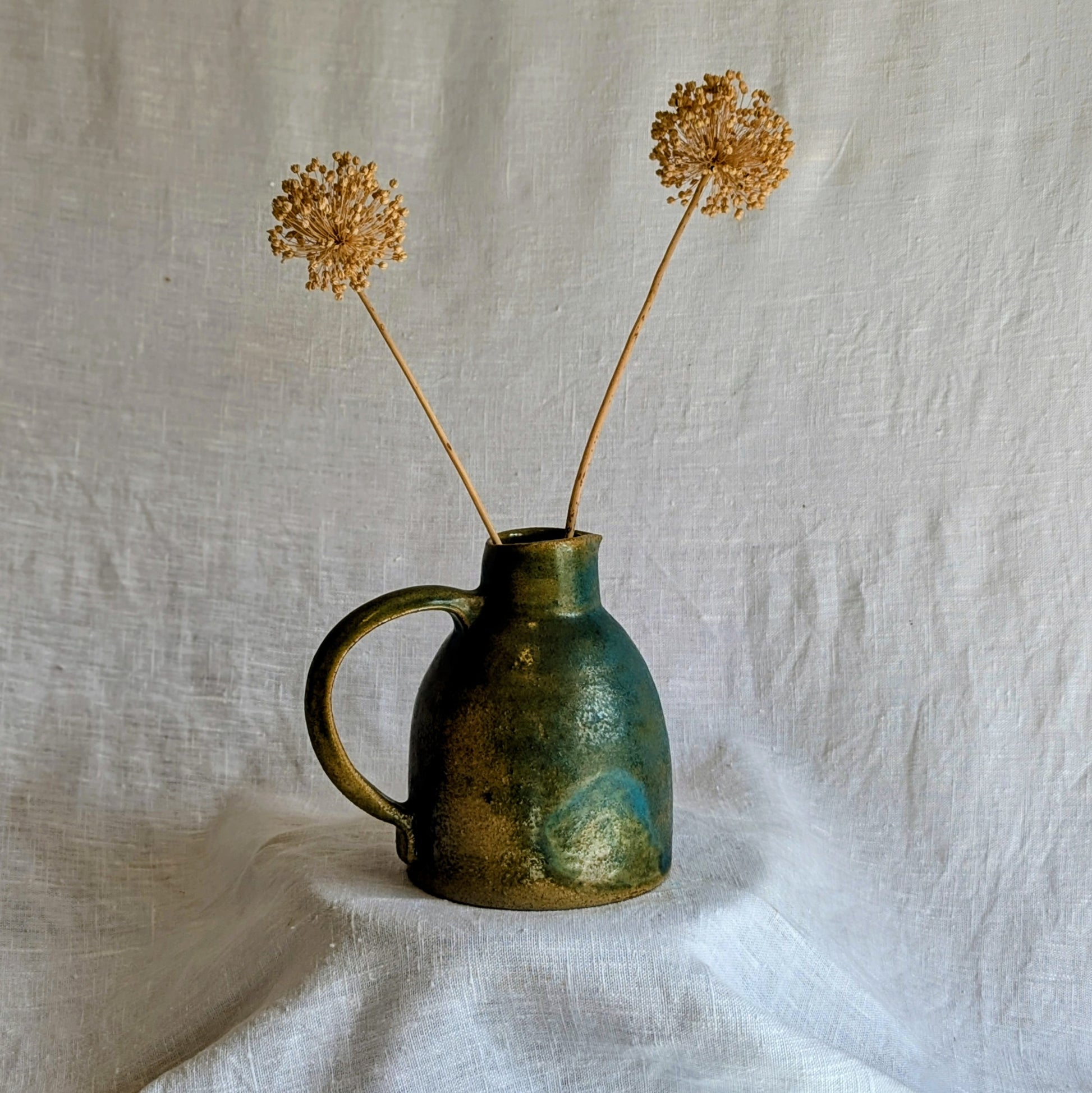 jarra artesanal en gres toffee esmaltado en tonos verdes y azulados, cerámica funcional contemporánea