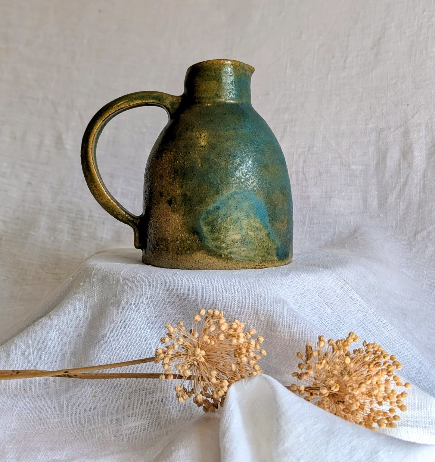 jarra artesanal en gres toffee esmaltado en tonos verdes y azulados, cerámica funcional contemporánea