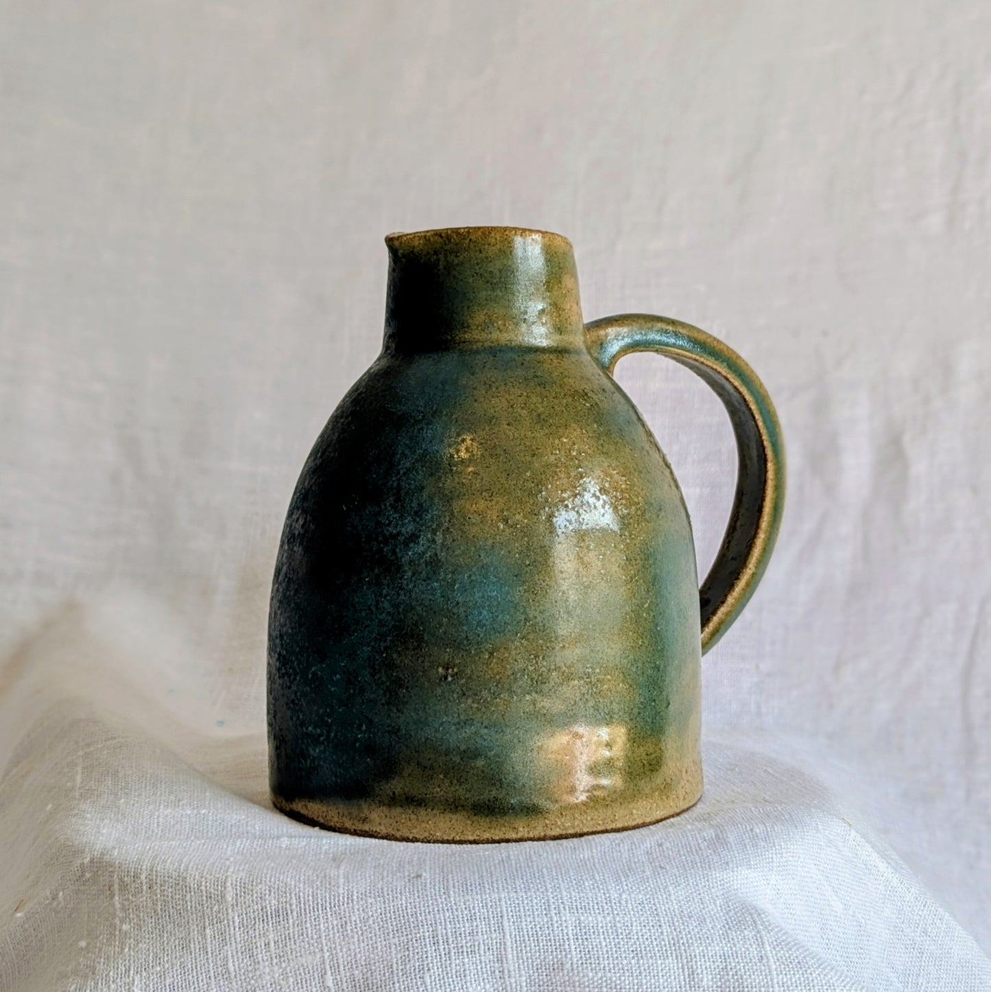 jarra artesanal en gres toffee esmaltado en tonos verdes y azulados, cerámica funcional contemporánea