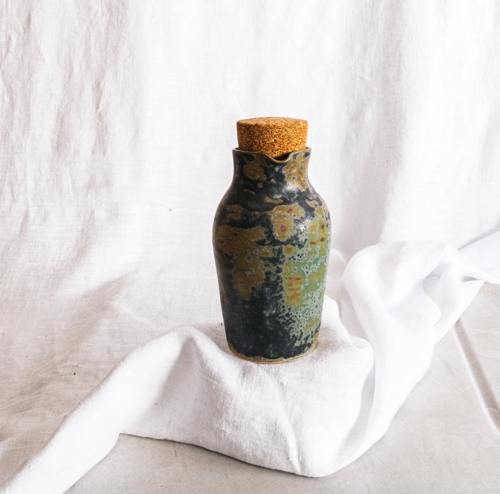 botella artesanal en terracota con esmalte verde reactivo y acabado moteado
