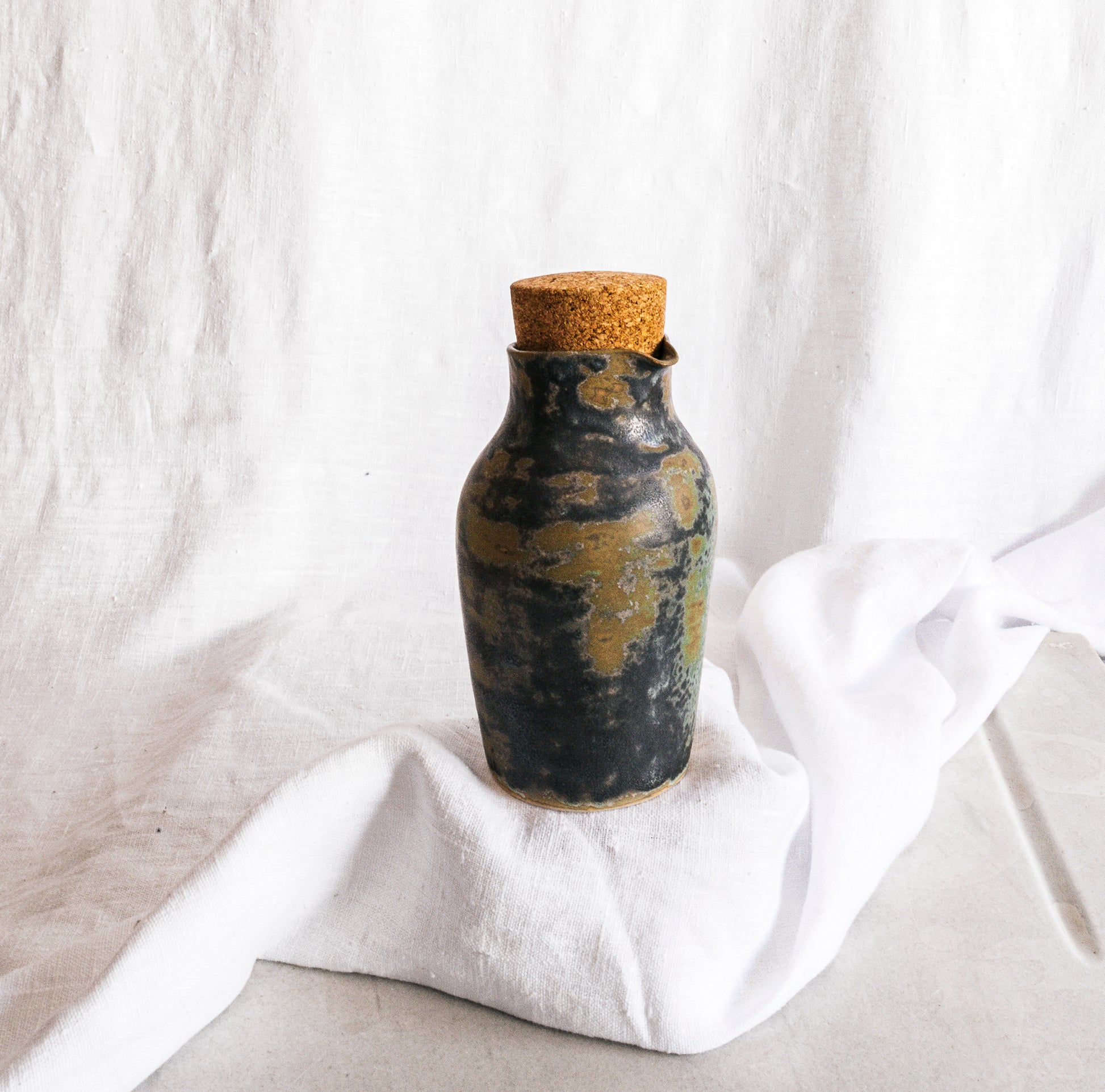 botella artesanal en terracota con esmalte verde reactivo y acabado moteado
