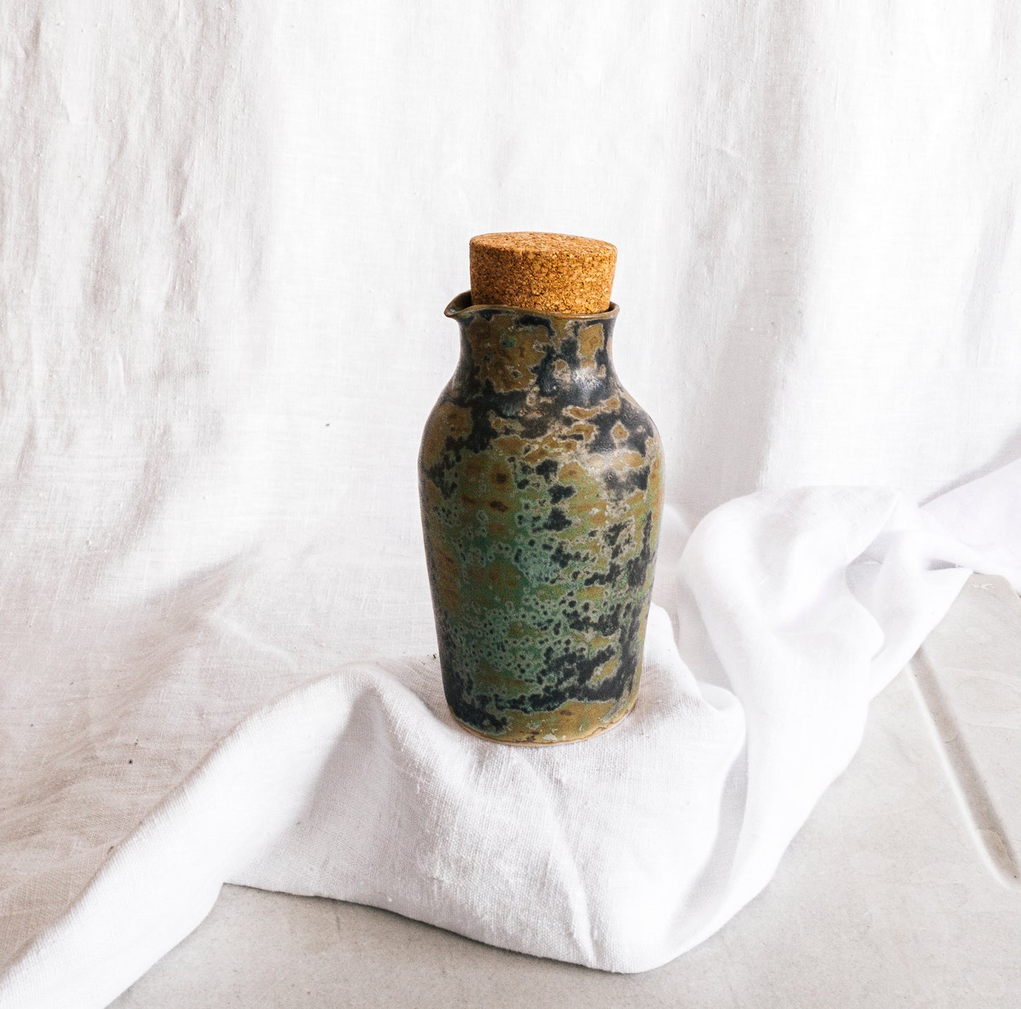 botella artesanal en terracota con esmalte verde reactivo y acabado moteado
