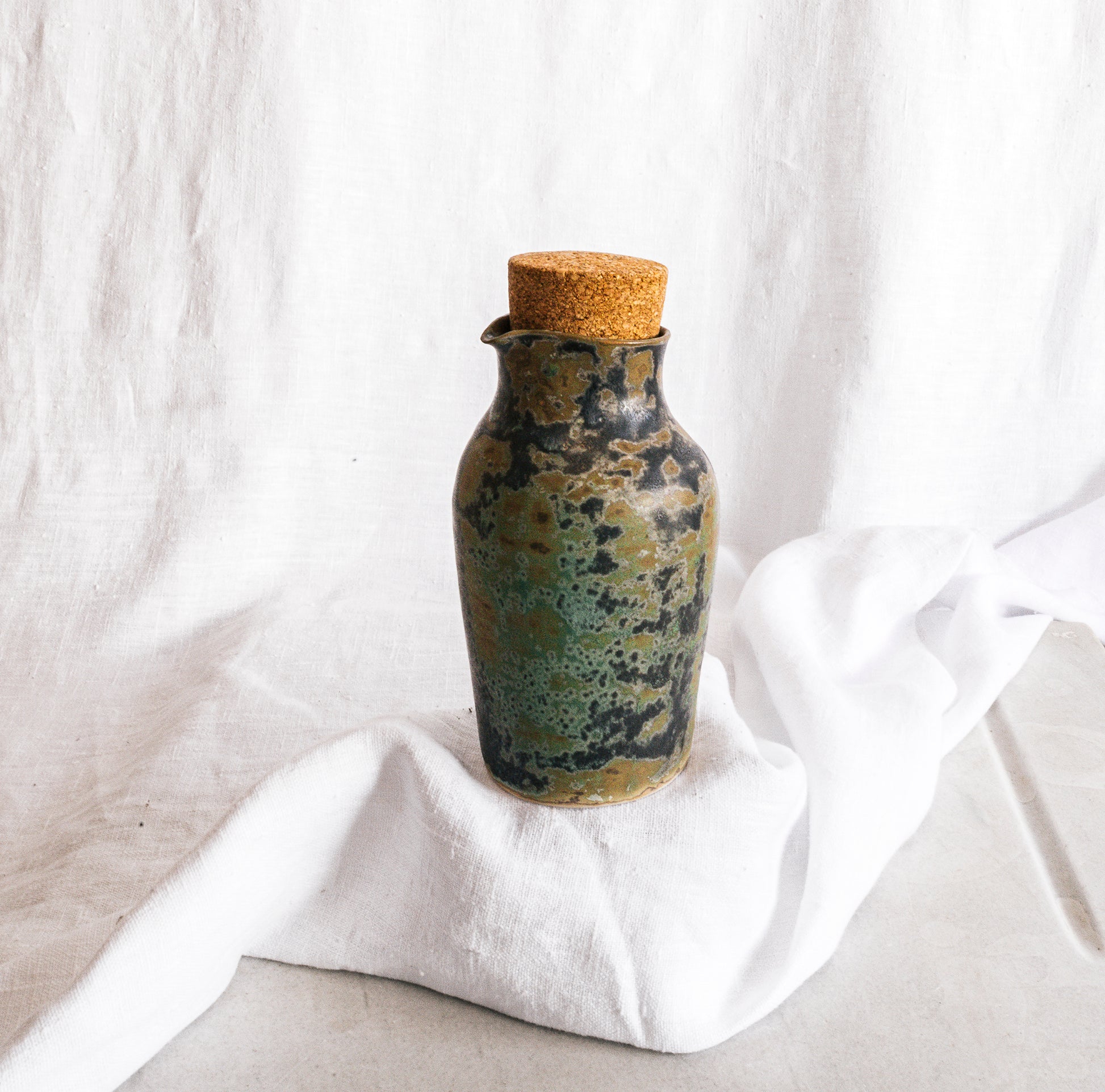 botella artesanal en terracota con esmalte verde reactivo y acabado moteado
